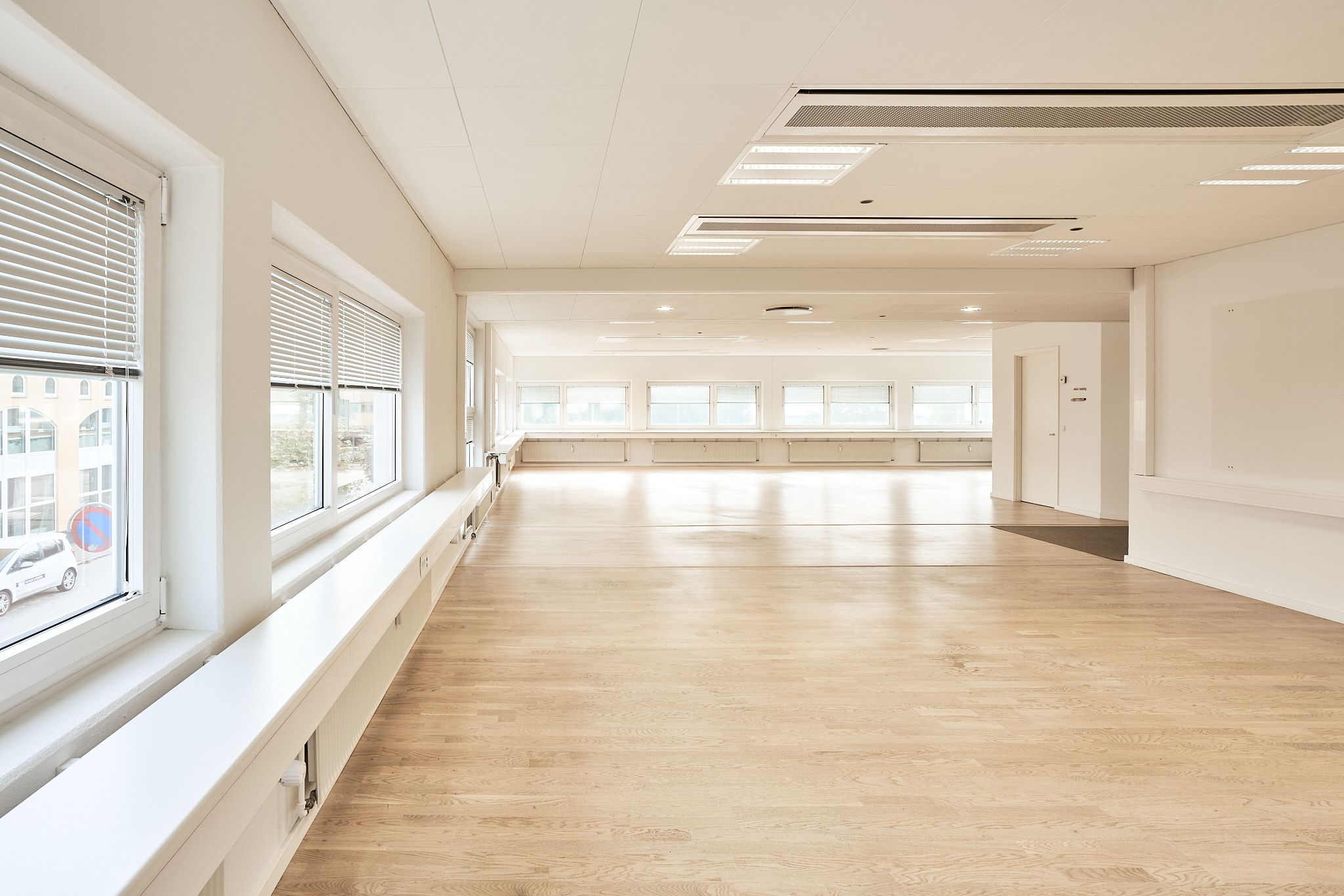 En stor, lyse hall med højt gulv og hvide vægge og vinduer, der giver masser af lys og en åben følelse