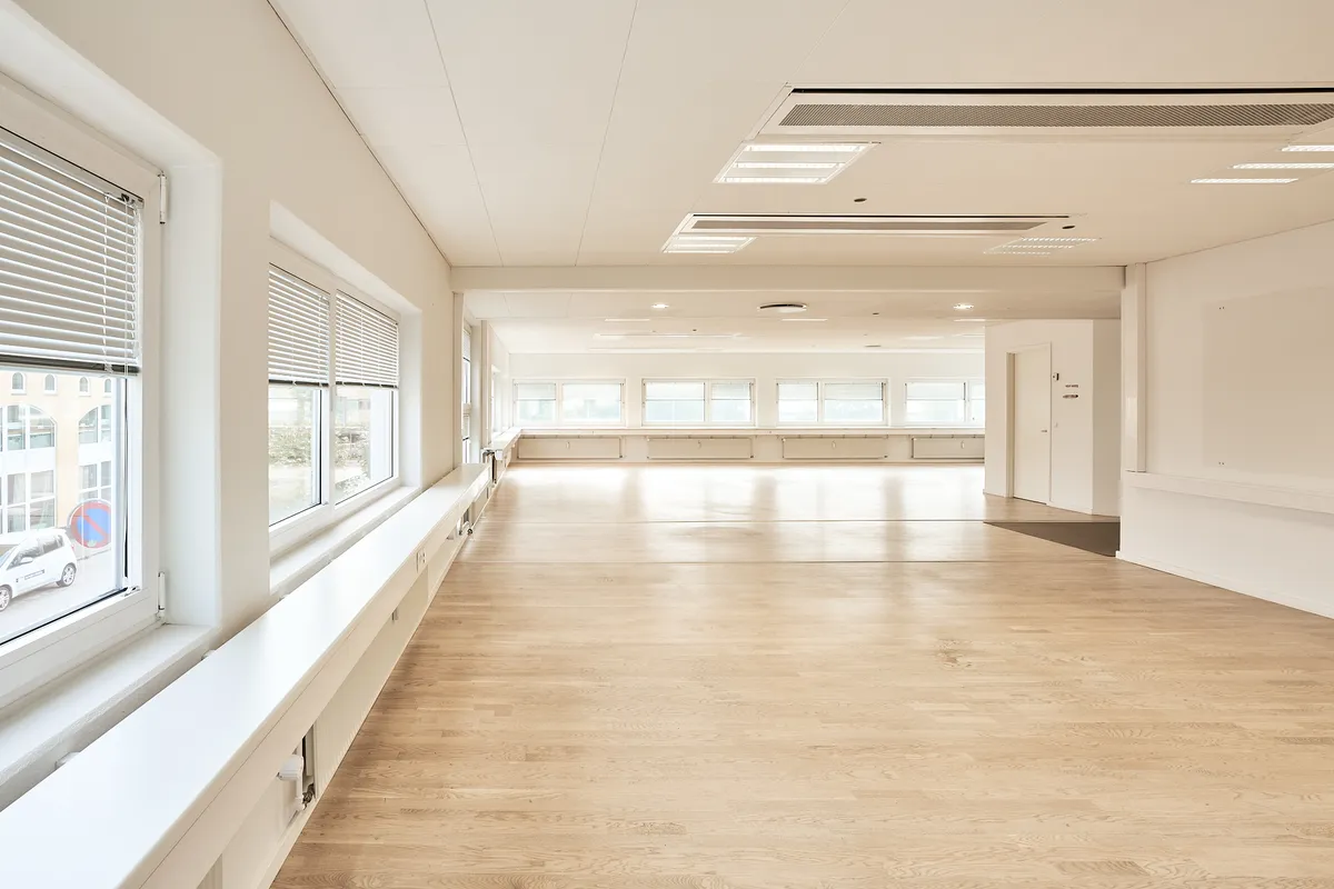 En stor, lyse hall med højt gulv og hvide vægge og vinduer, der giver masser af lys og en åben følelse