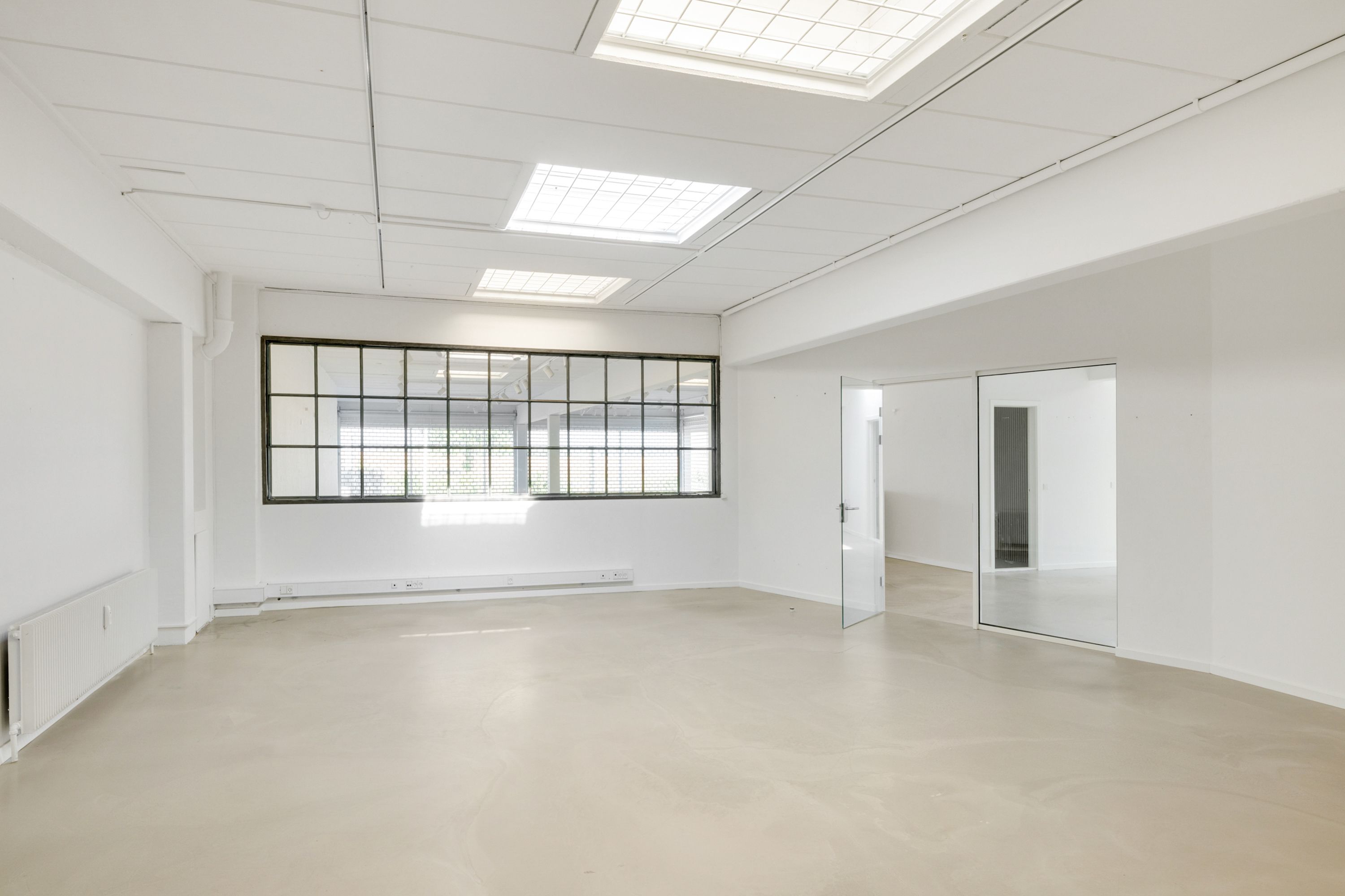 Store vinduer med lyse lofter og hvide vægge, hvilket giver meget lys og en indbydende atmosfære. Lokalet er ubeskrevet og