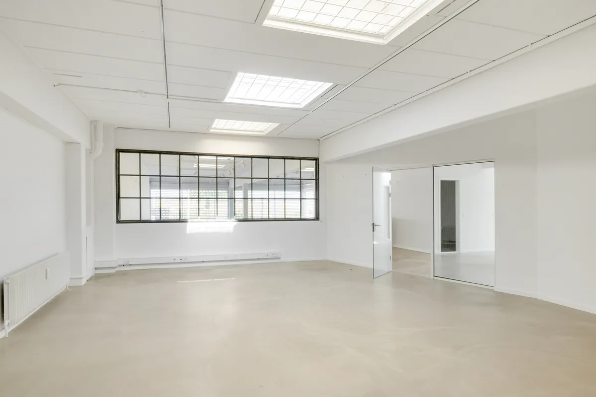 Store vinduer med lyse lofter og hvide vægge, hvilket giver meget lys og en indbydende atmosfære. Lokalet er ubeskrevet og