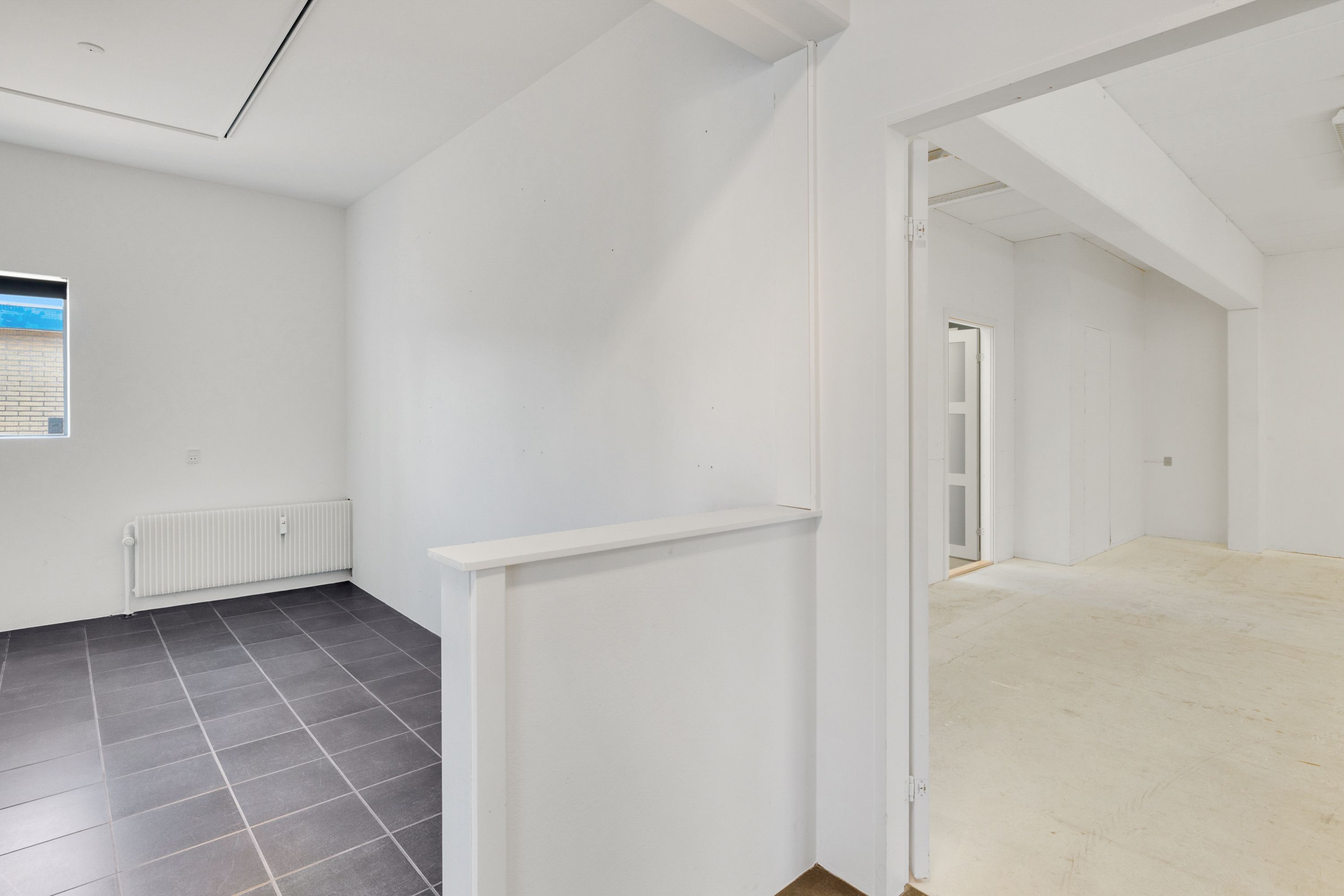 Kortere gange med hvide vægge og gulv og en radiator, der er monteret på væggen
