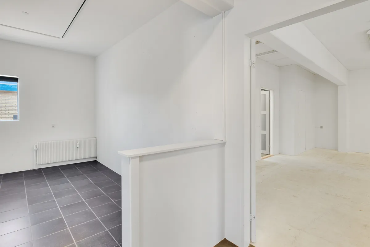 Kortere gange med hvide vægge og gulv og en radiator, der er monteret på væggen