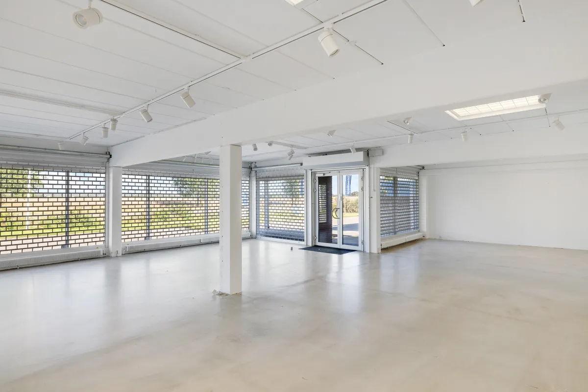 Store, moderne lokaler med hvide vægge, lysekroner og store ruder til showroom med kontor. Lokalerne er pænt og rummelige