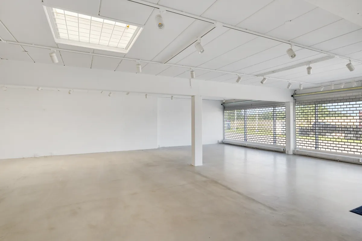 Tomt lokale med hvidt loft og gulv, udstyret med moderne lysekroner og ventiler samt udsigt til udenfor