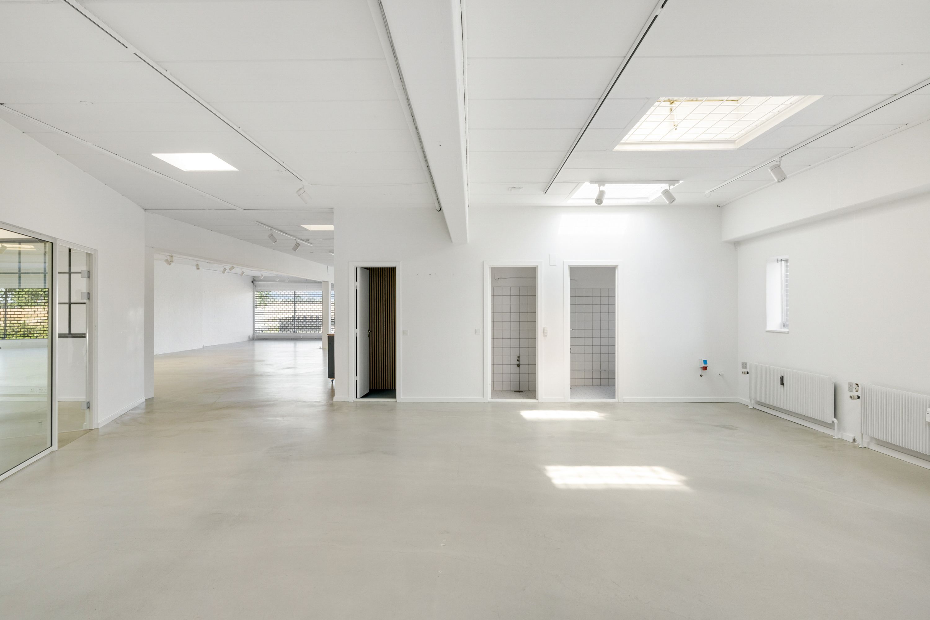 Lejemålet tilbyder store og lyse lokaler med hvide vægge, lysekroner, vindu og spejl, samt to toiletrum og et kontor med et