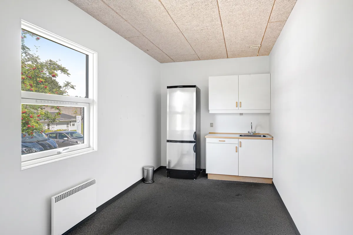 I en hvid malet erhvervspark med en køleskab og et køkken med en hvid vaskebøtte og hængende hvidt skab