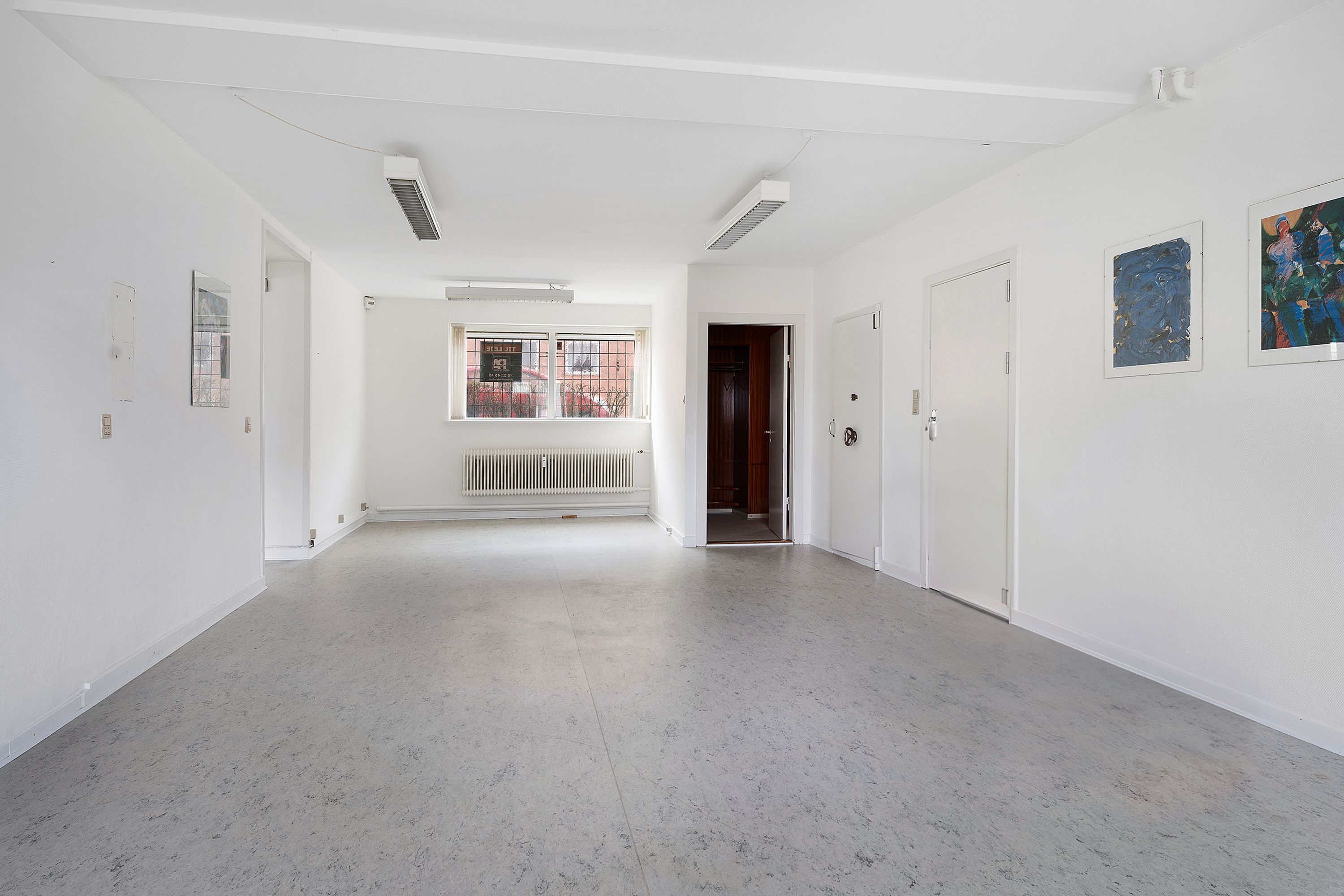Lejlighed med en stor hal, to døre og tre malerier på væggen, hvor det er køligt og lyse.