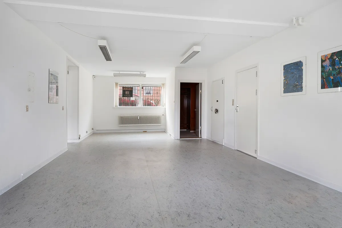Lejlighed med en stor hal, to døre og tre malerier på væggen, hvor det er køligt og lyse.