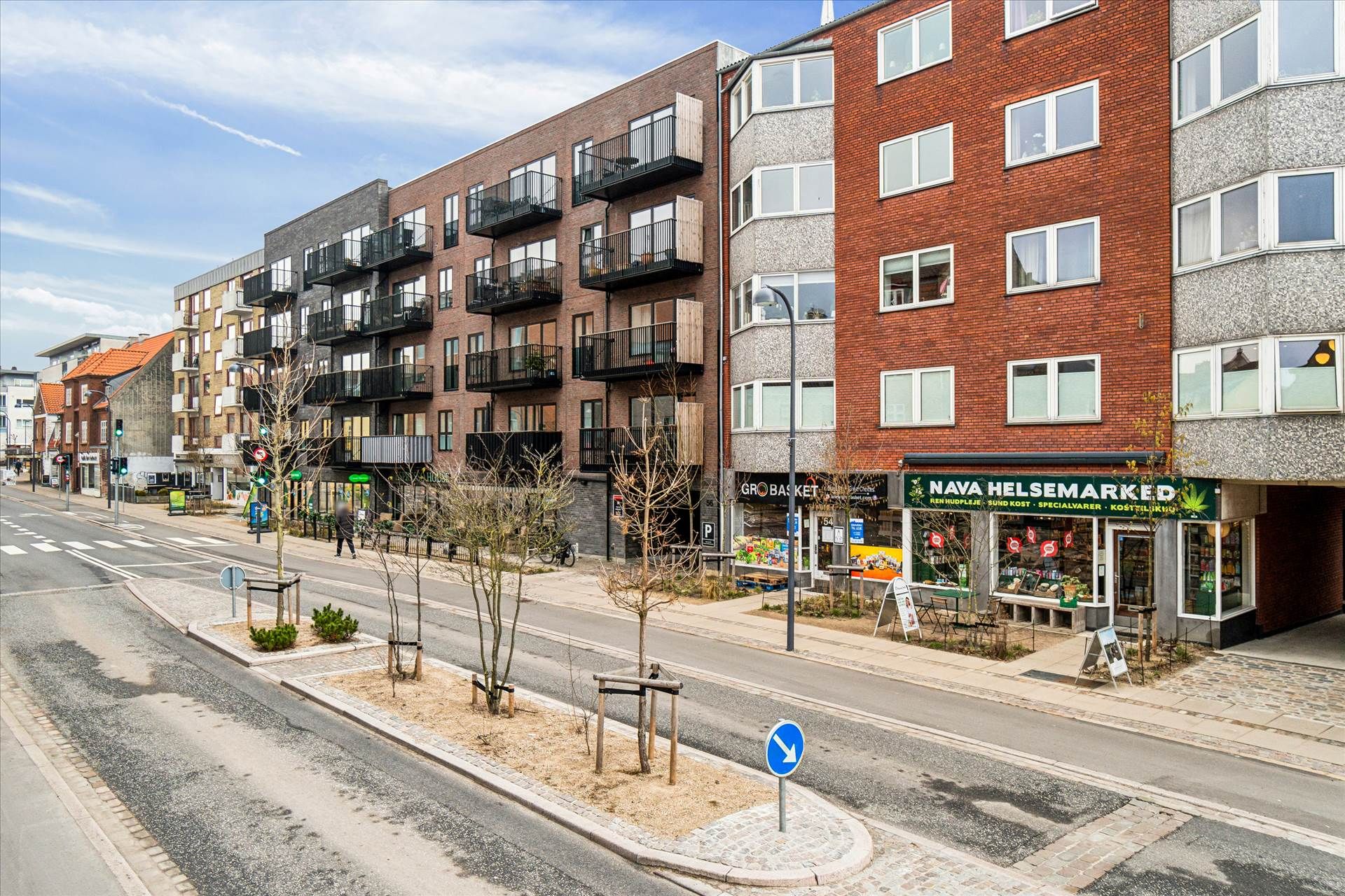 Butikslokaler med balkoner og en grøn vækst på øverste etage og et møbelforretning på hjørnet