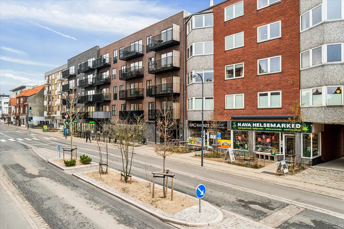 Butikslokaler med balkoner og en grøn vækst på øverste etage og et møbelforretning på hjørnet