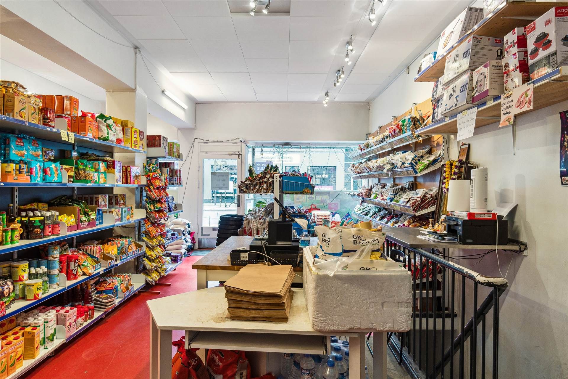 En stor lagerhal med flere hylder med snacks og snacks, fuld af produkter, en kasse med papirposer og flere sække med