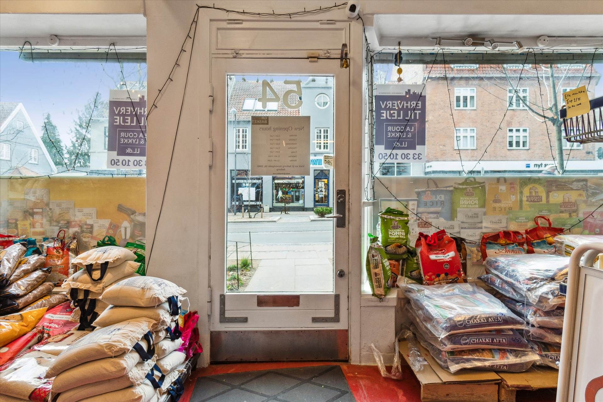 En forretning med åben dør og mærketekster på væggen og vinduet, samt produkter og sække på gulvet