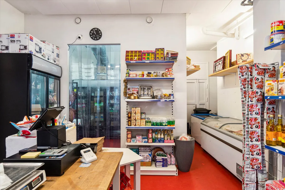 Lejemål med salgsareal og køleskab, hylder med produkter og kasseapparat samt køleskab og kassevogn i kælderen