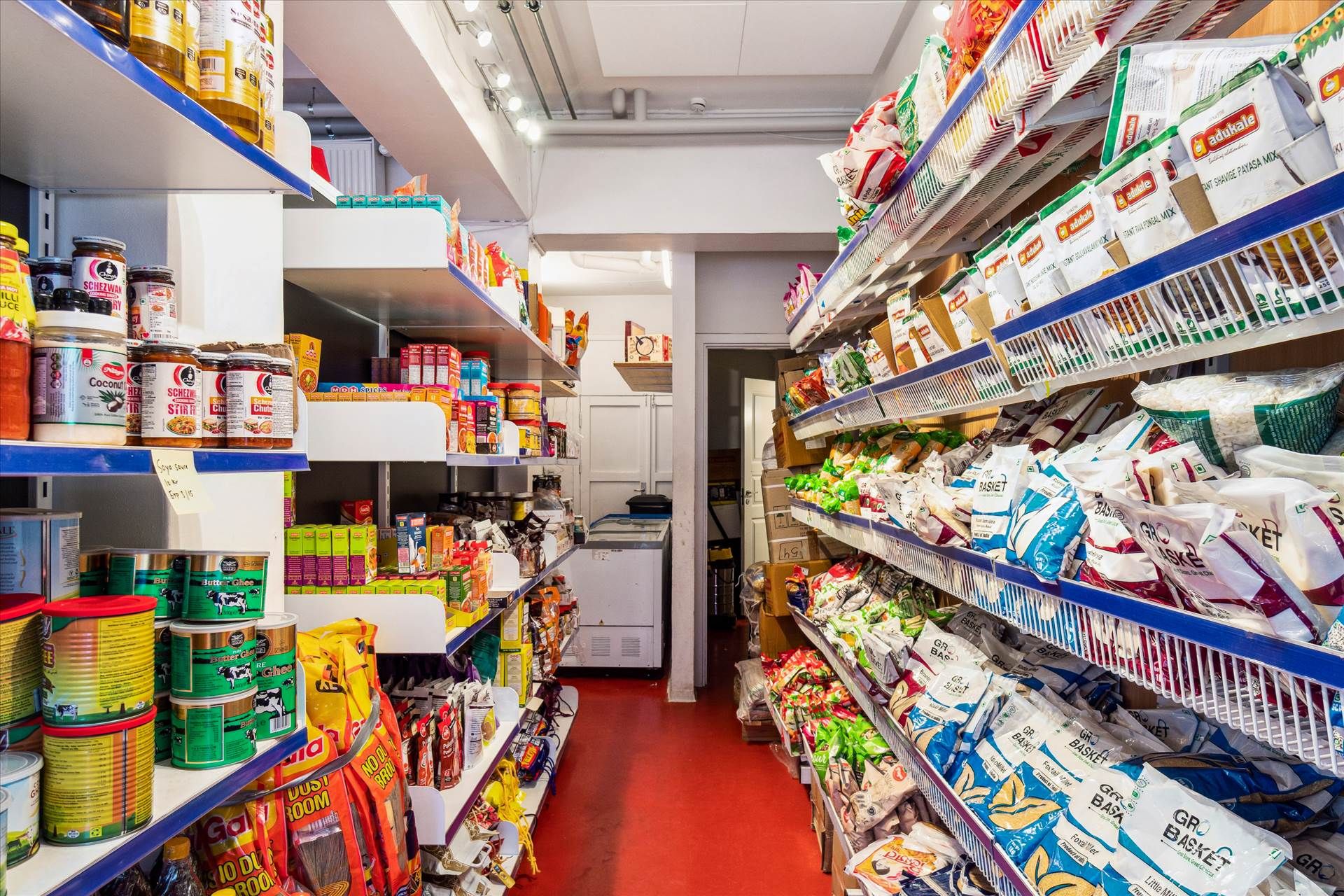 Butik med mange emballerede produkter, krydderier og snackmad, samt flere salgsreoler med forskelige produkter og salgskurve.