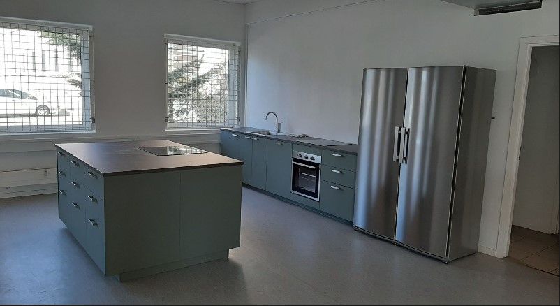 Moderne køkken med højloft, øvre hylder, gaskomfur, indbygget ovn, to køleskabe, skabe og en ø.