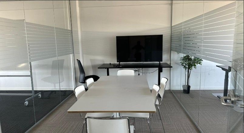 Mødeværelse med moderne design og luksuriøs indretning. Værelset indeholder en stor, fladskærmsfjernsyn, en hvid