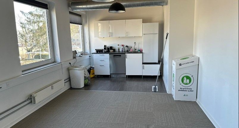 Nyistandsat køkken med hvide skabe og rustfrit stål, gulvbelægning, vindue og moderne indretning.