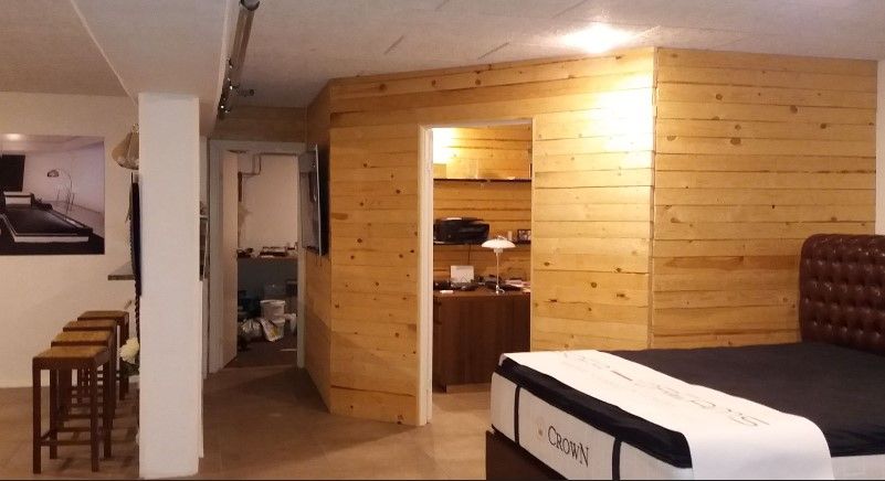 En lille soveværelse med moderne design og lyse loftsbelægninger samt en massiv trævæg og et stort dobbeltseng med mørke