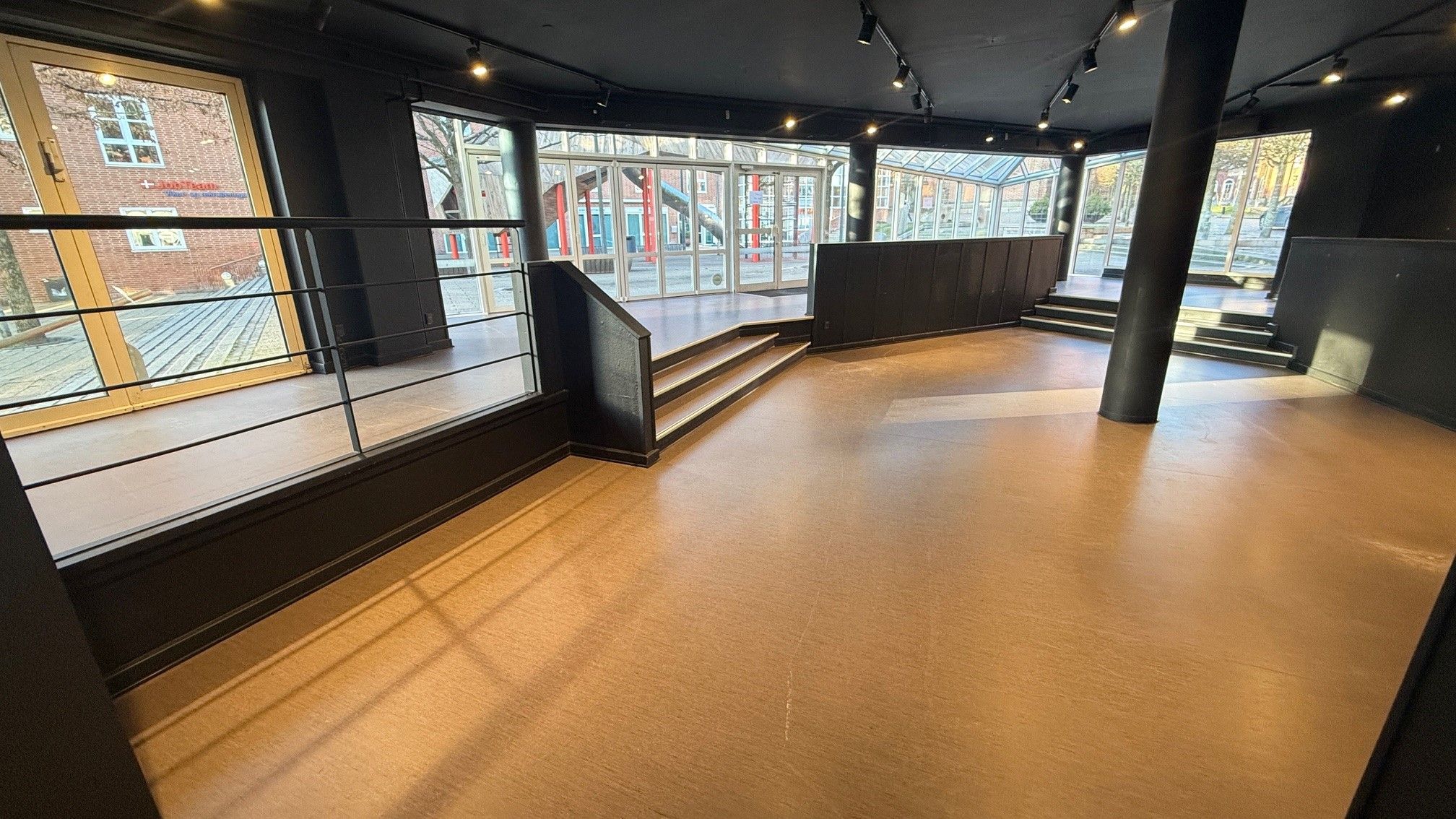 Indenfor en moderne indretning med lysgule gulvbelægning og udsigt til gaden med træer og bygninger