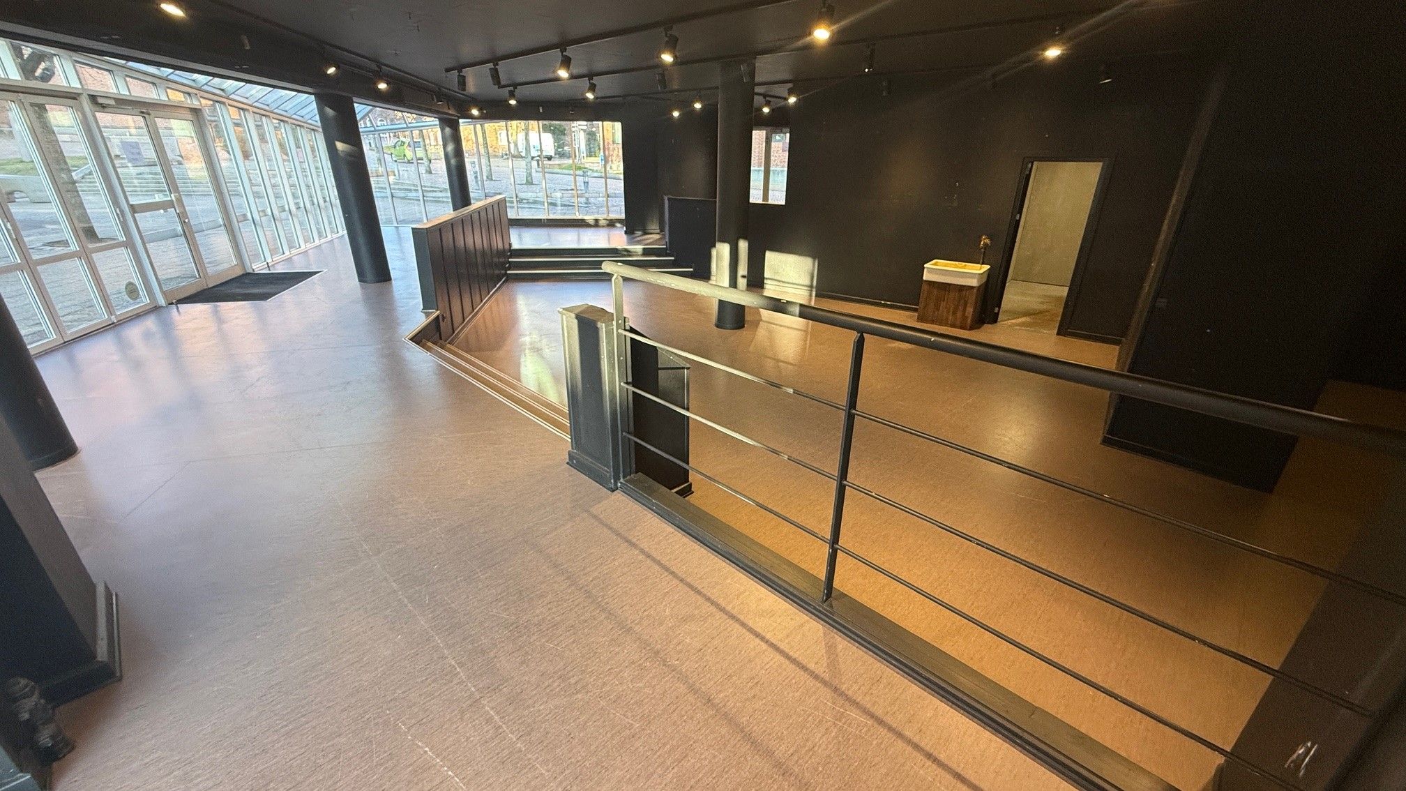 En indgangshal med lyse loftsbelægning og slanke gulvprofiler i lysbrun nuance, sammen med lysekroner og lyse spotlys for at