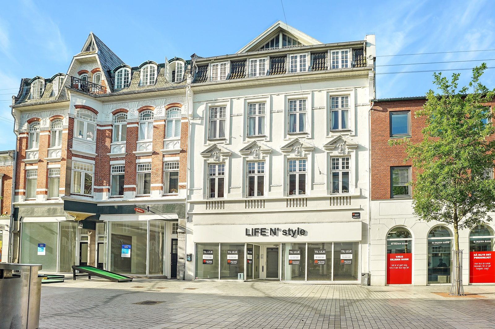 En hvid facade med butiksvinduer, Life N'style butiksfront, røde vinduer, nydelig udsmykning, smukt vejareal, bymidte,