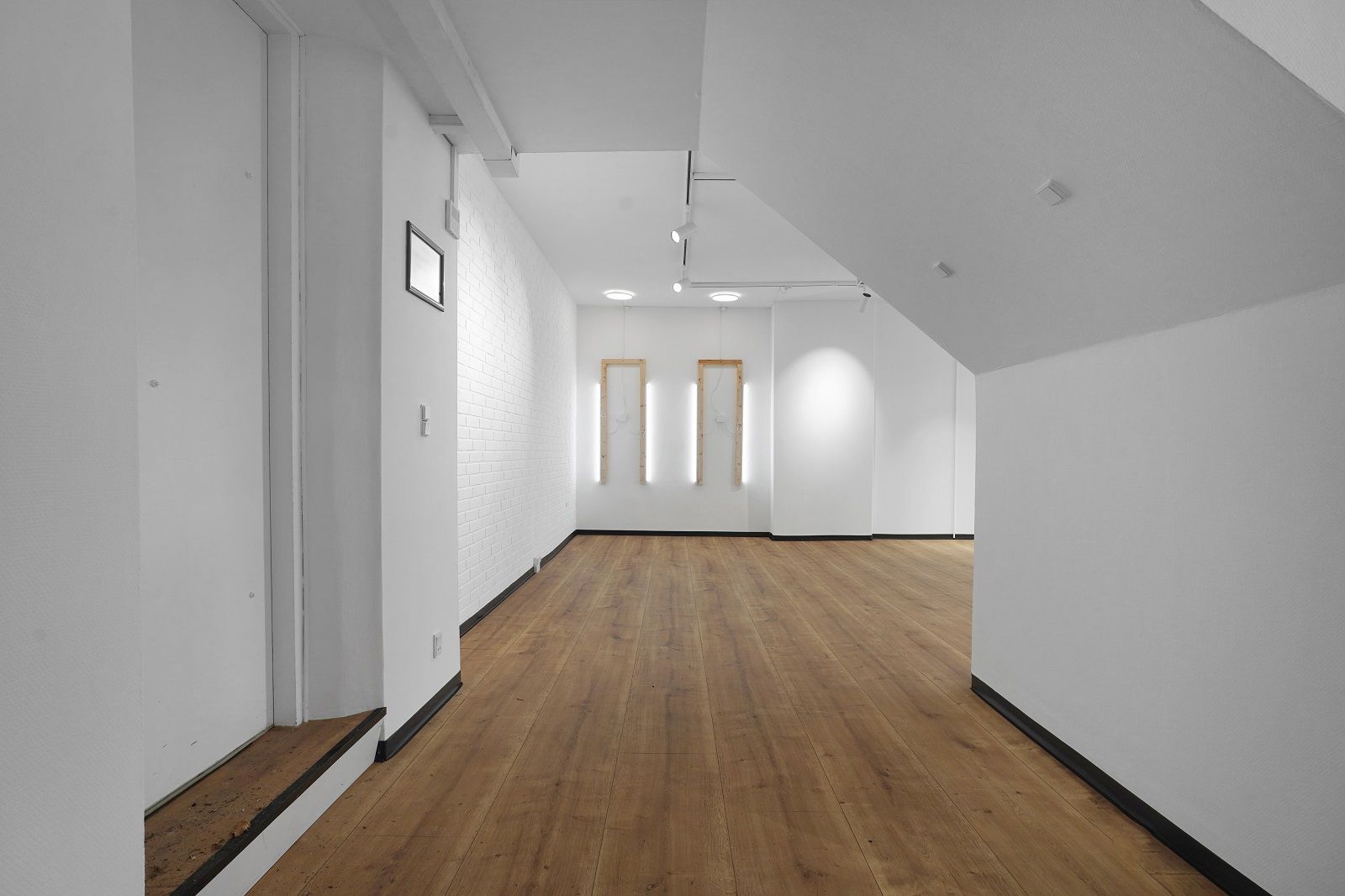 Store, moderne kontorlokaler med højt til loftet og lyse loftsvinduer. Lys, åben rum med hårdt, trægulv og hvide vægge. To