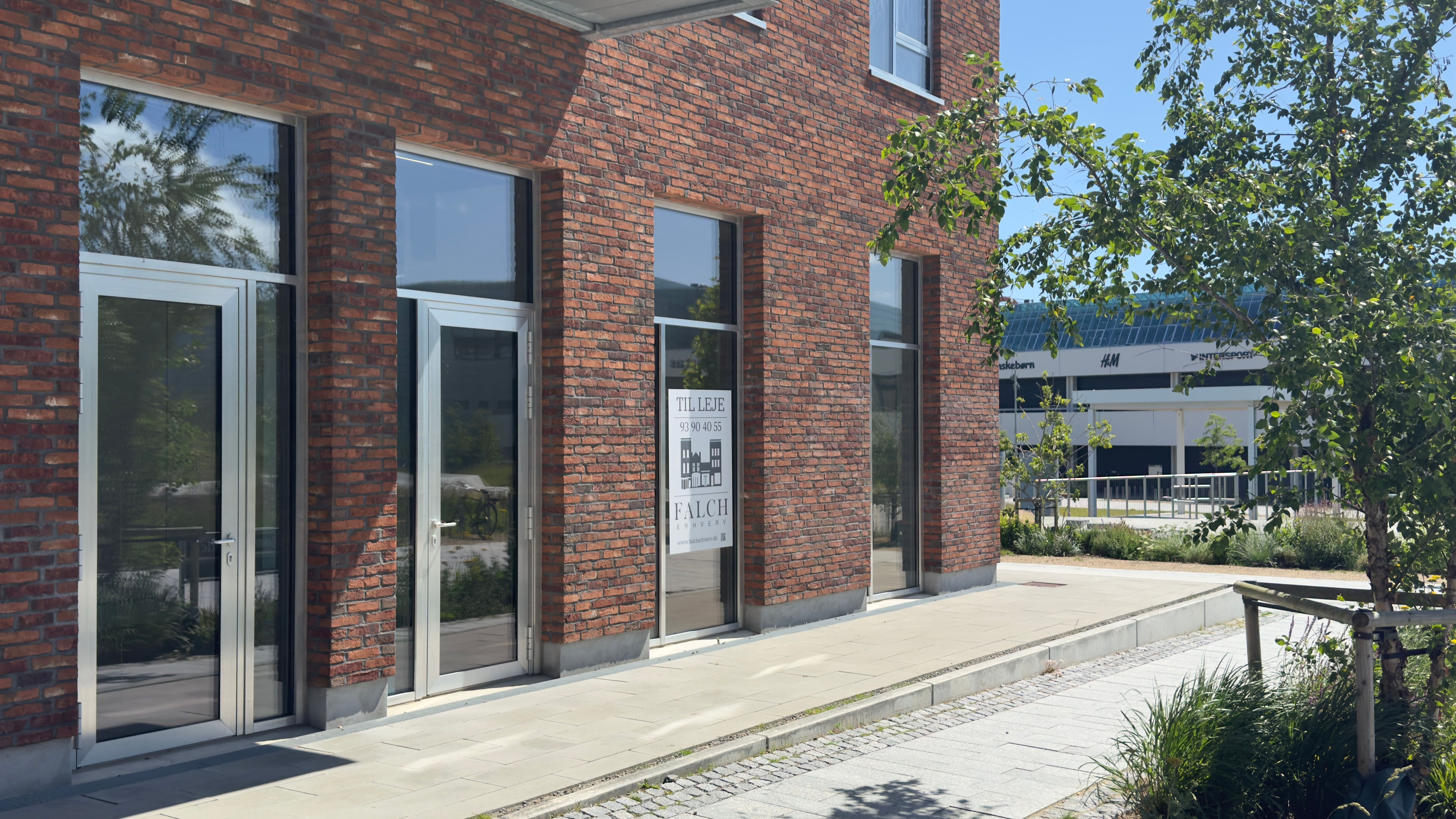 Indvendigt og moderne kontordør til Falch Erhverv i Høje Taastrup, med glasvinduer og plantekanter udenfor