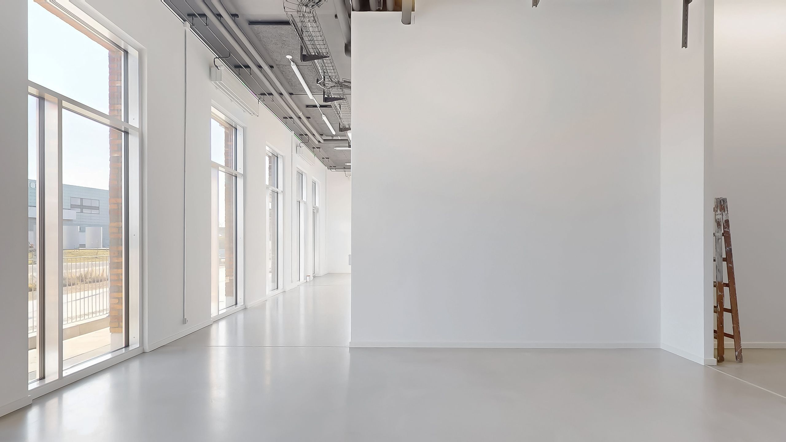 Indvendigt billede af en stor, tom og hvid væg, gulvet er renset og uden møbler eller andet indhold