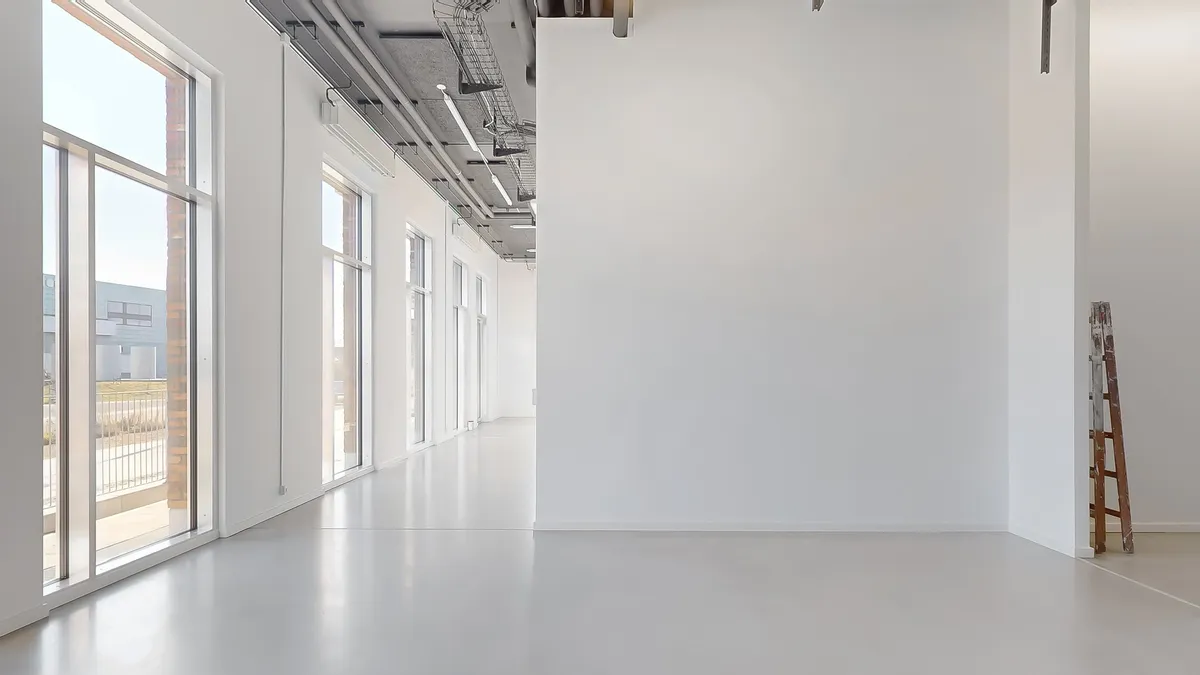 Indvendigt billede af en stor, tom og hvid væg, gulvet er renset og uden møbler eller andet indhold