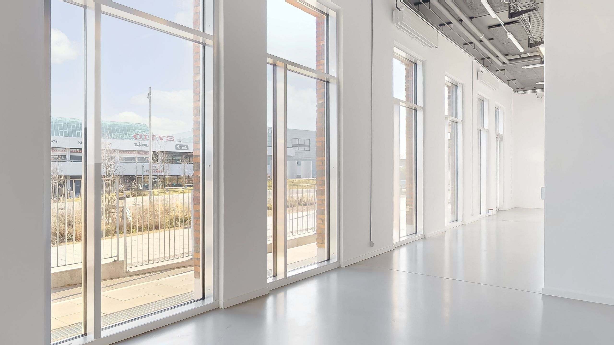 Moderne kontorlokaler med større vinduer og indvendige glasdøre, der giver masser af naturligt lys og en åben følelse i