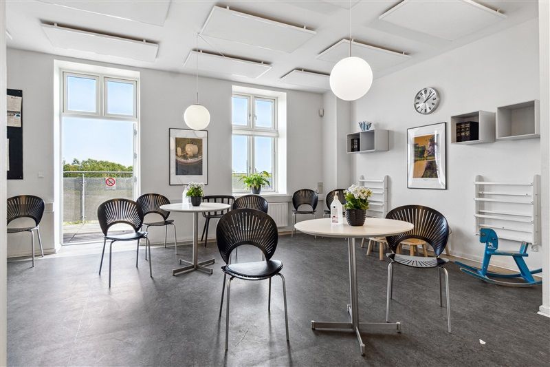 Første sal med lyse lofter og møbler, vinduer med udsigt til grønne træer og rekvisitter i et rent og velorganiseret rum