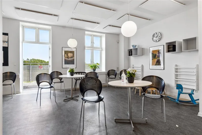 Første sal med lyse lofter og møbler, vinduer med udsigt til grønne træer og rekvisitter i et rent og velorganiseret rum