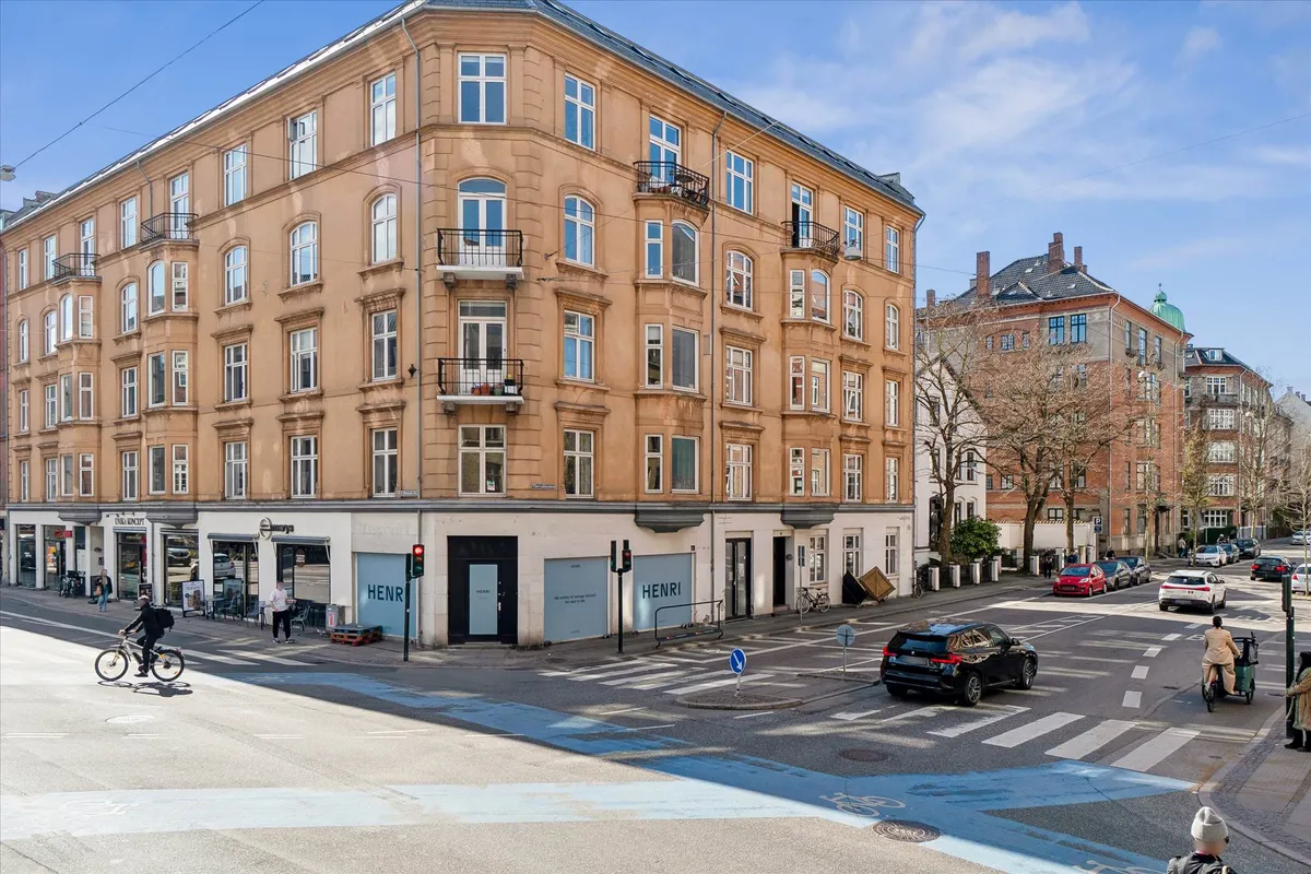 Mennesker cykler og går på en travl krydsning med biler og cykelskulpturer i baggrunden