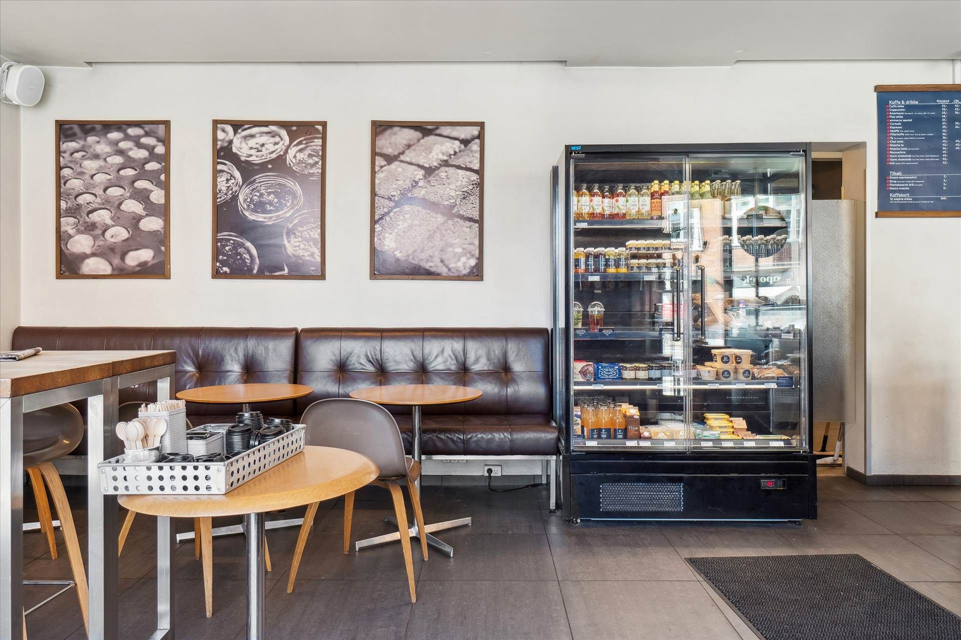 En elegant indretning med lædersofa, rundt bord og en køleskab med snacks og drikke.