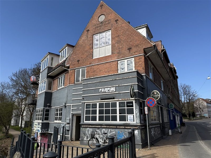 Ansigtsmalerier med graffiti på facaden af et rødmalet hus, der ligger på Brogade i Odense