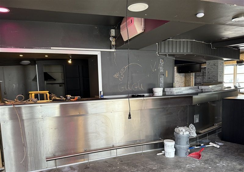 Køkken med udstykning og udstykning, hvor der er udstående kabler og støv, samt kasser og snavsede værktøjer på gulvet.