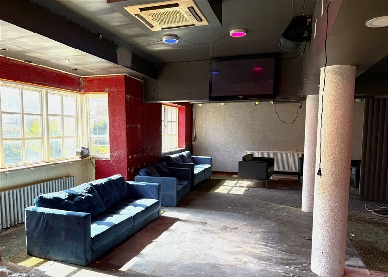 Inde i et lokale er der røde vægge, gulve og loft samt tre blå sofaer og en sort stol. Der er flere lysepunkter på loftet og