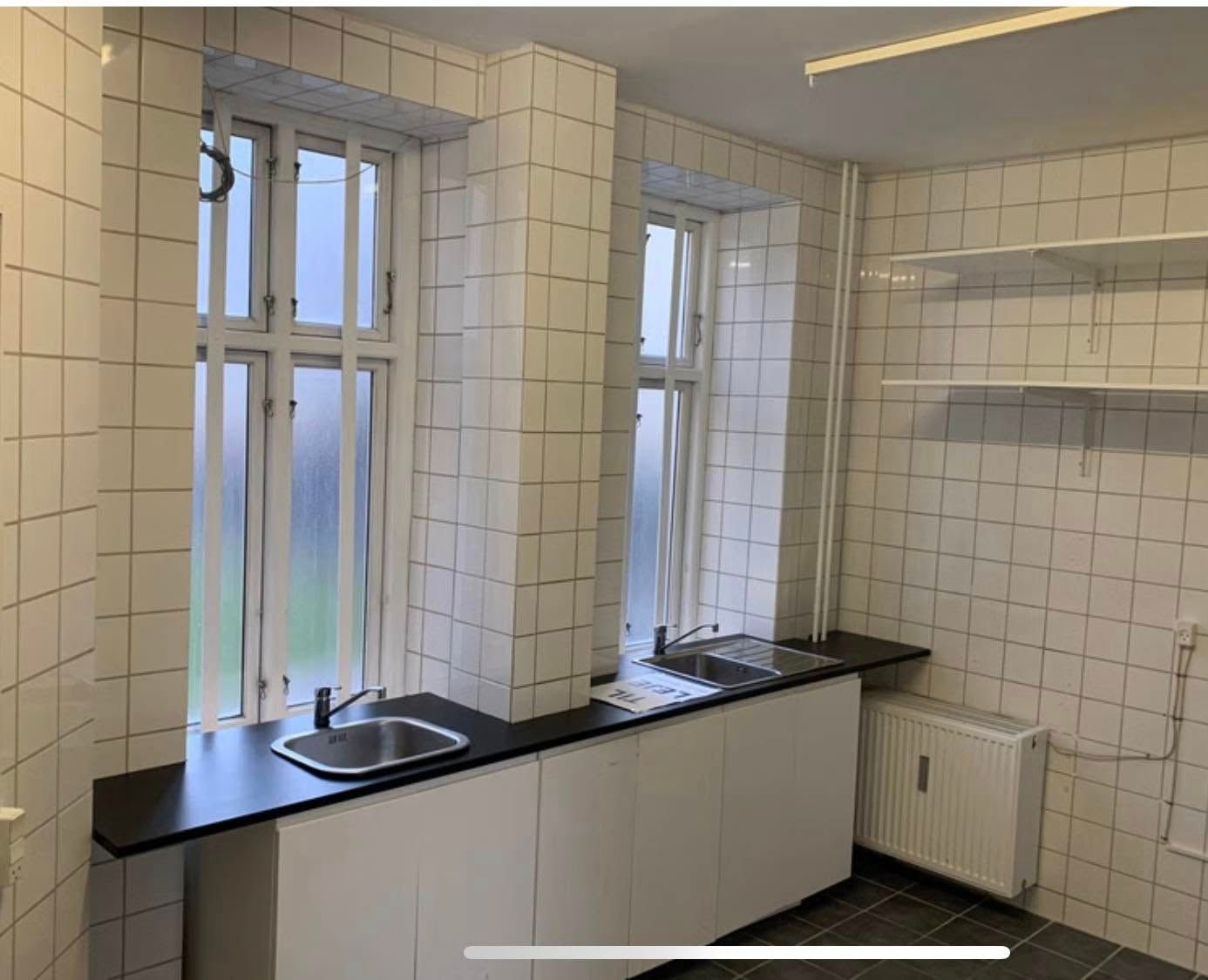 En køkken med to enkeltpersoner og en dobbelt person i en lejlighed med køkken udstyret med to lysegreb og to vandhaner samt