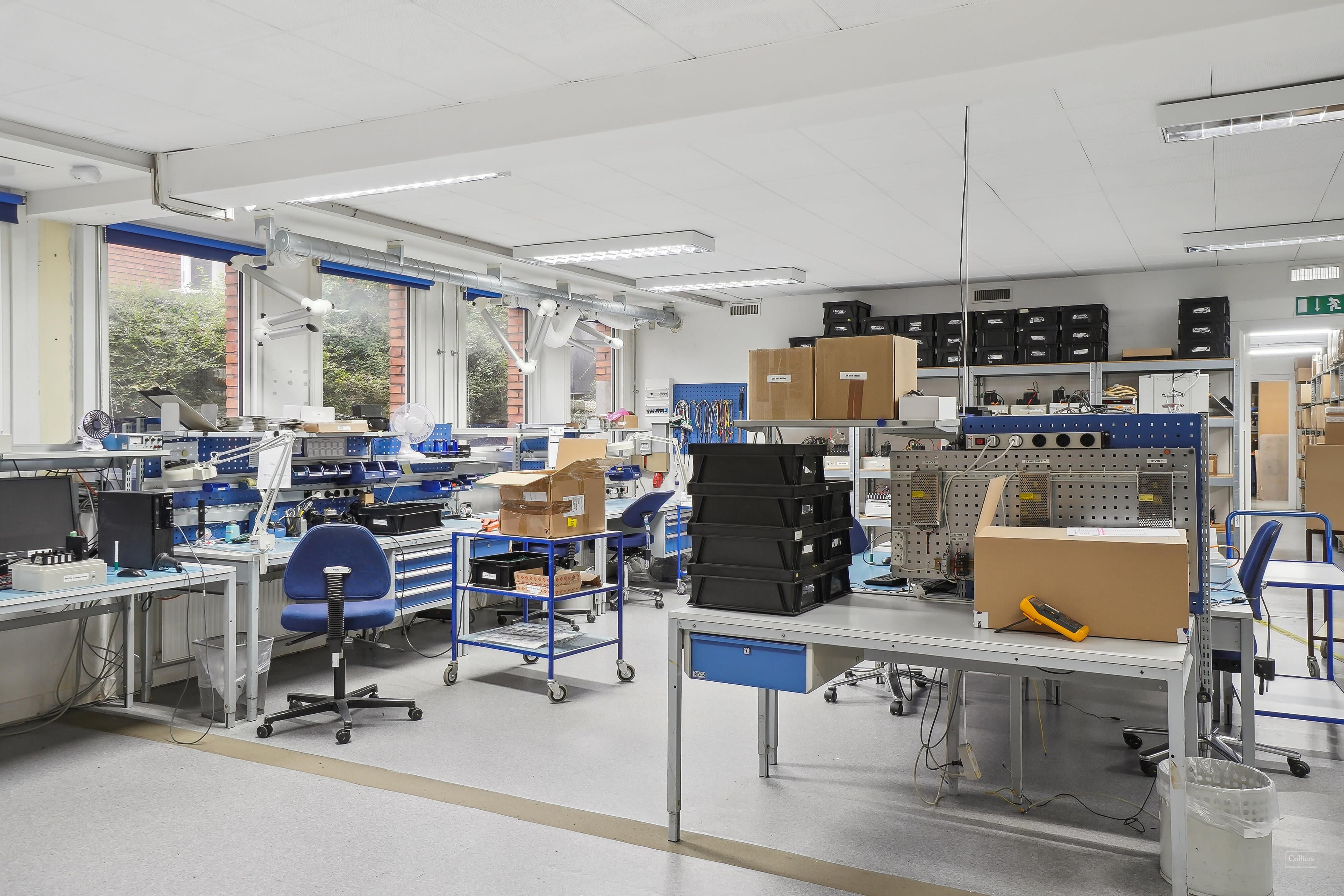 Dansk kontor med skriveborde, stole, kasser og flere apparater til elektronisk forarbejdning og montage