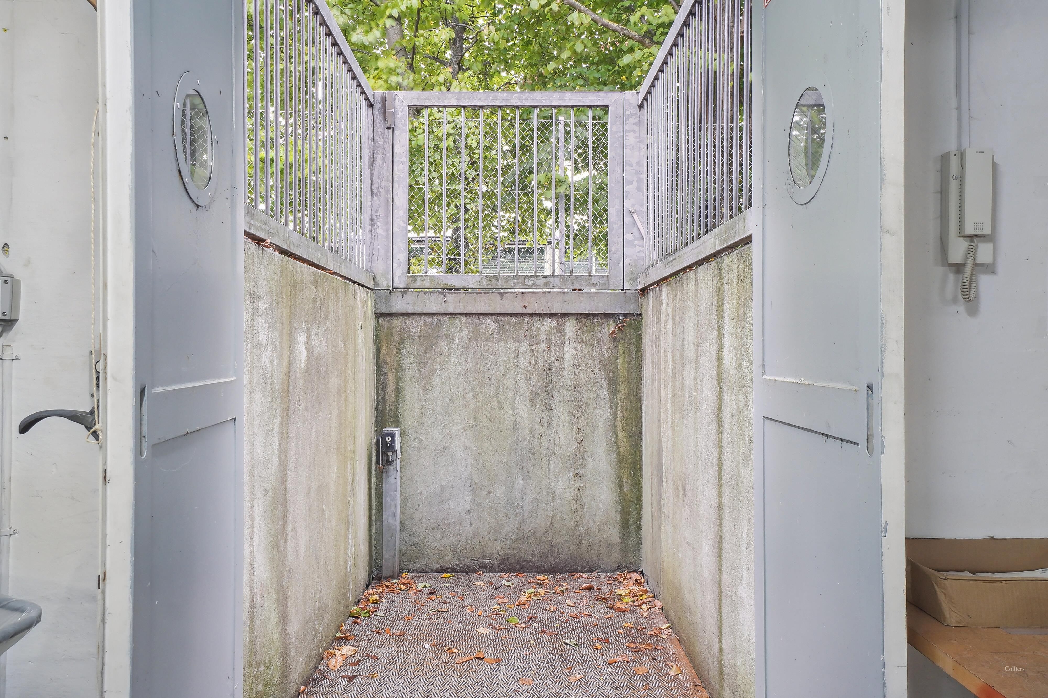 Rådgivende kontorer med elevator, to høje døre, ventileret glasdør og ringeskærm på væggen, samt højdemåler og trægulve i