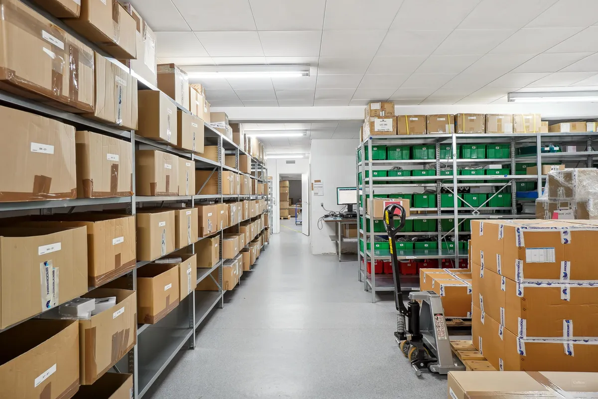 Lager med kasserne og bokse i rækker og gulv med et forkæft og gulvet er træslibet.