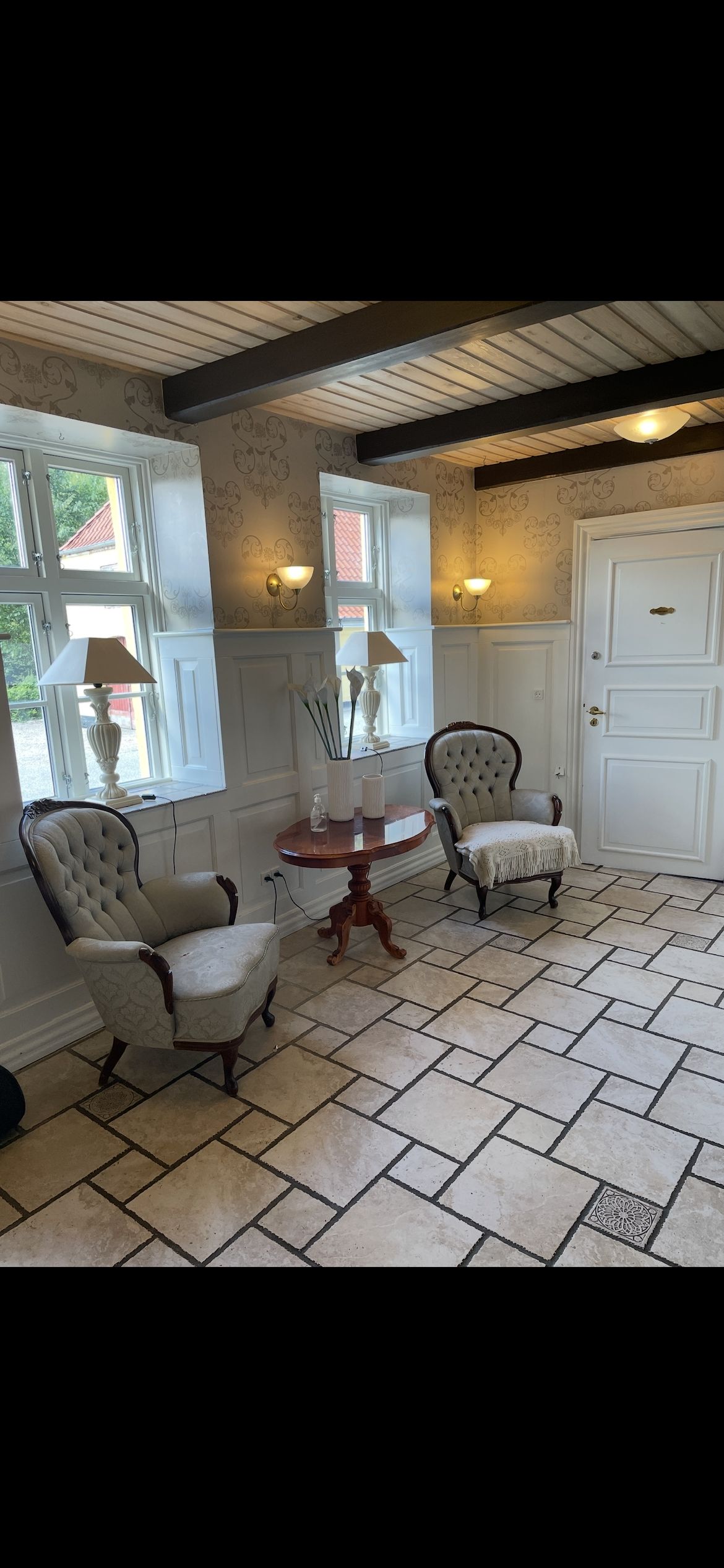 Moderne stue med lyse og pæne møbler og lysekroner samt lysegulve og vindue med udsigt til haven