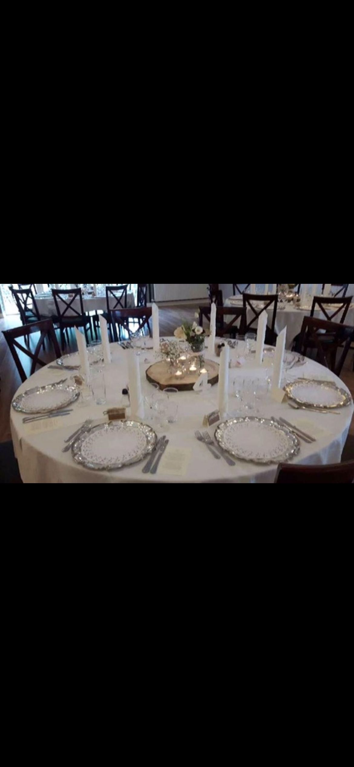 Et elegant bord med et sølvserviet og et blomstercenter på et hotel med hvide duge og lyse stearinlys