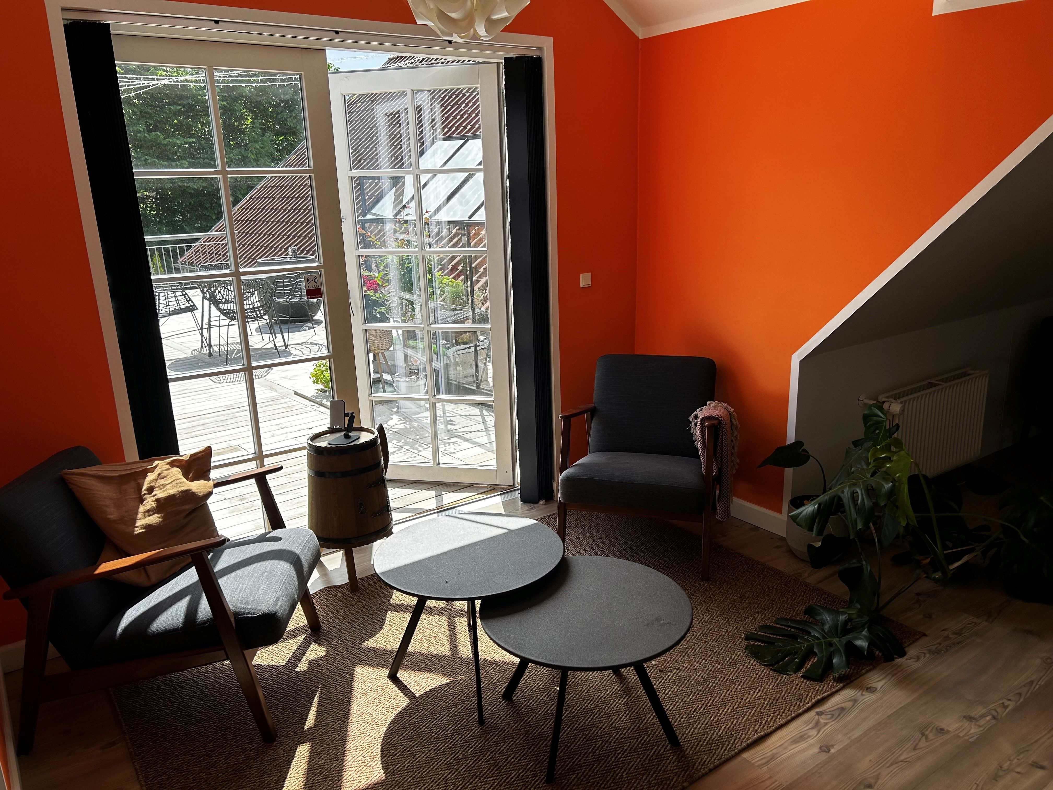 Komfortabel stue med to møbler og to runde borde på tæppe med sofa, lysekroner og vinduer til terrasse