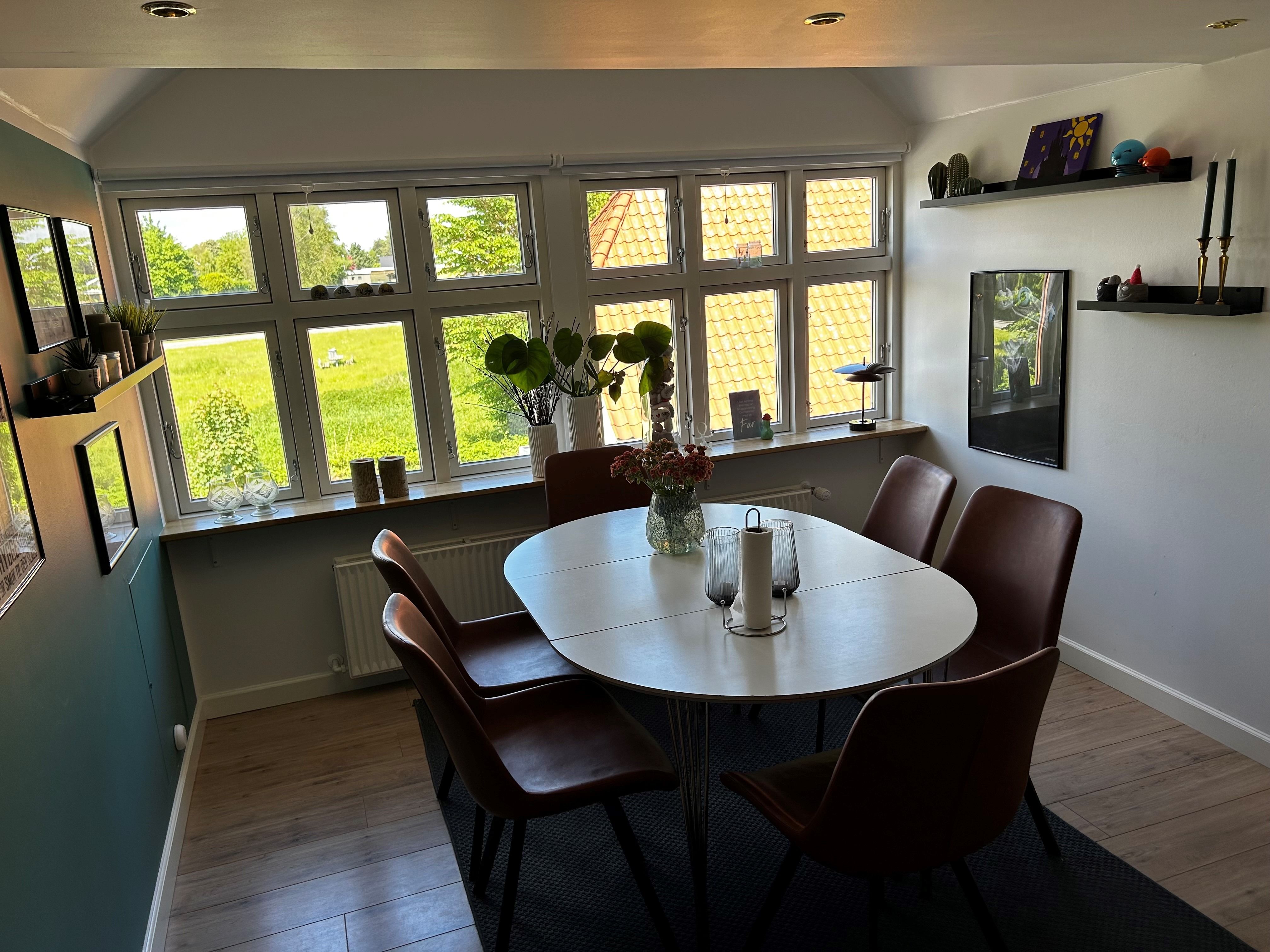 Et moderne køkken med lyse vinkler og en rund spisebord med blomster i en vase og lysekroner