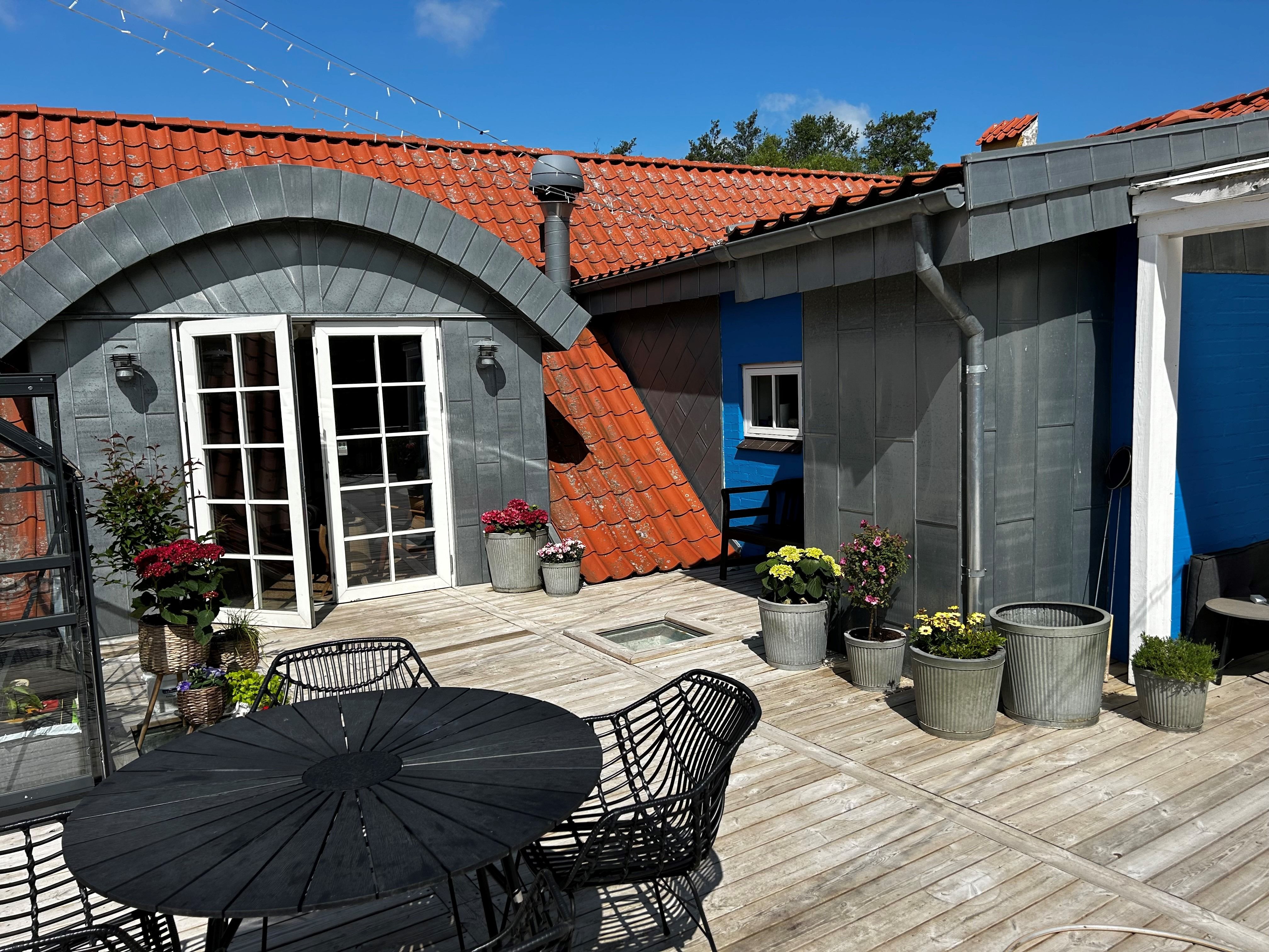 Det er et sommerhus med en have og et terrasse med bord og stole