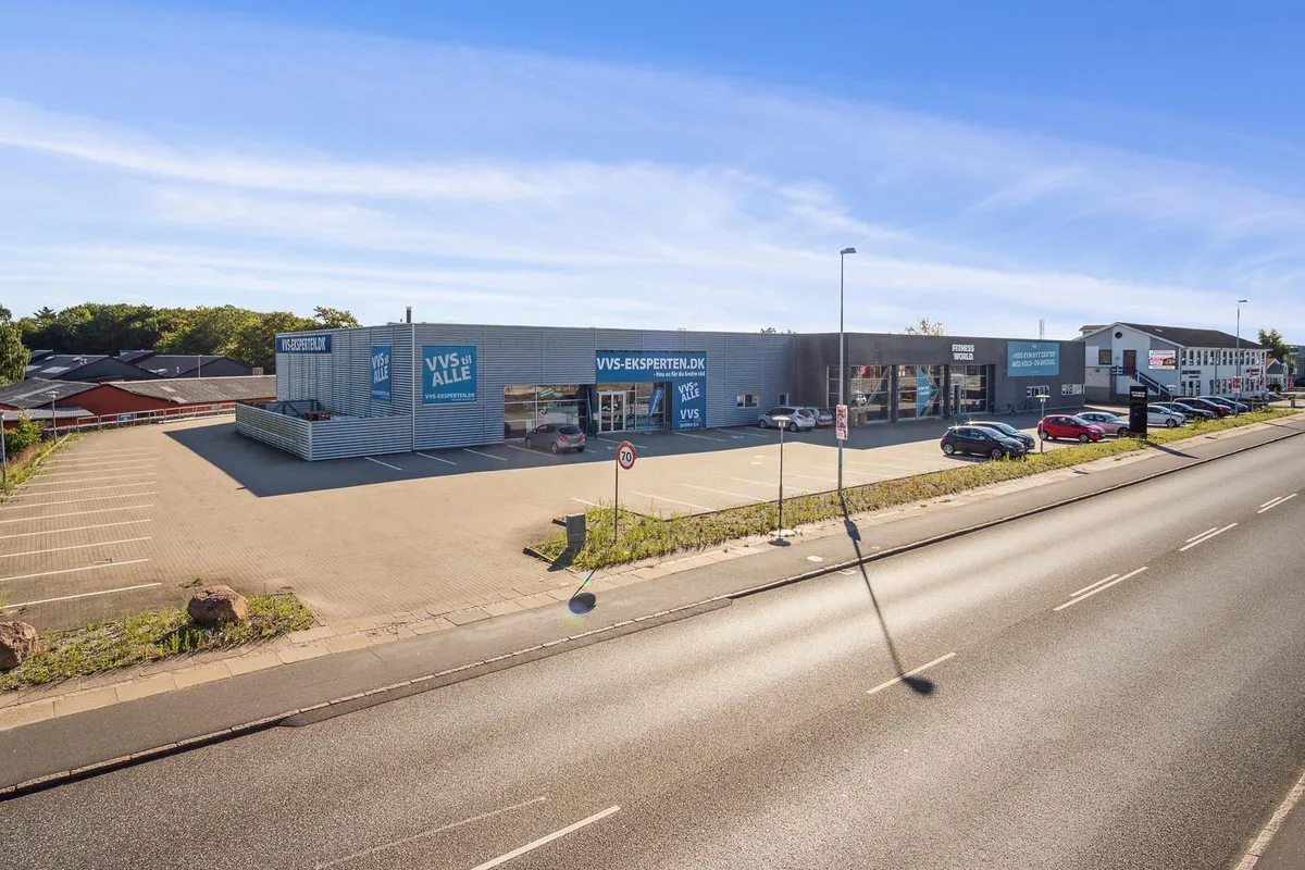 Et lejemål i Randers med flere biler parkeret og et varetegn med teksten "VVS-EKSPERTEN.DK" på facaden