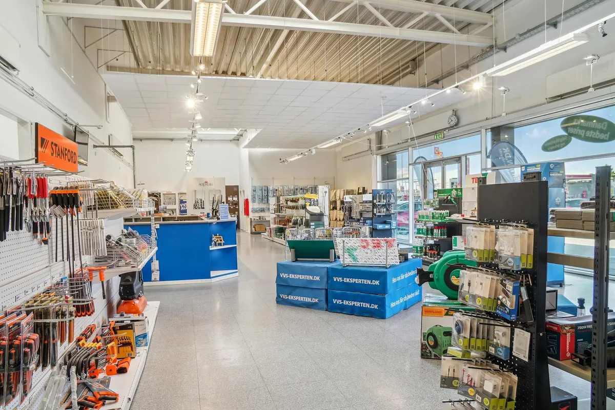 Forretning med diverse værktøj og produkter i et rektangulært lokale med højt lys og vinduer