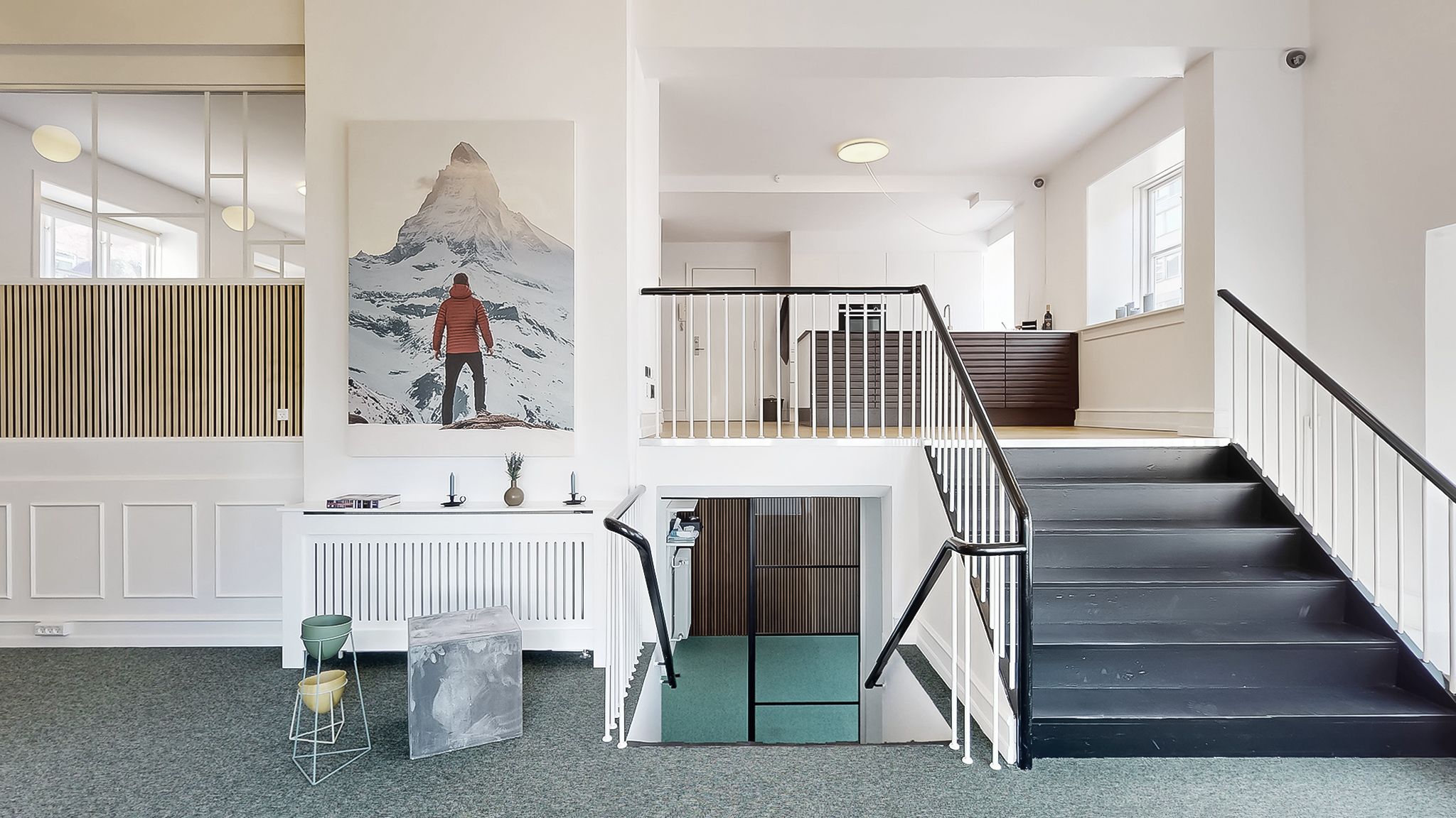 Støbeformet kunstværk og stol står på gulv. Stairs og håndtag er lavet i sort og hvidt. Væg er hvid og døre er brun. Maleri