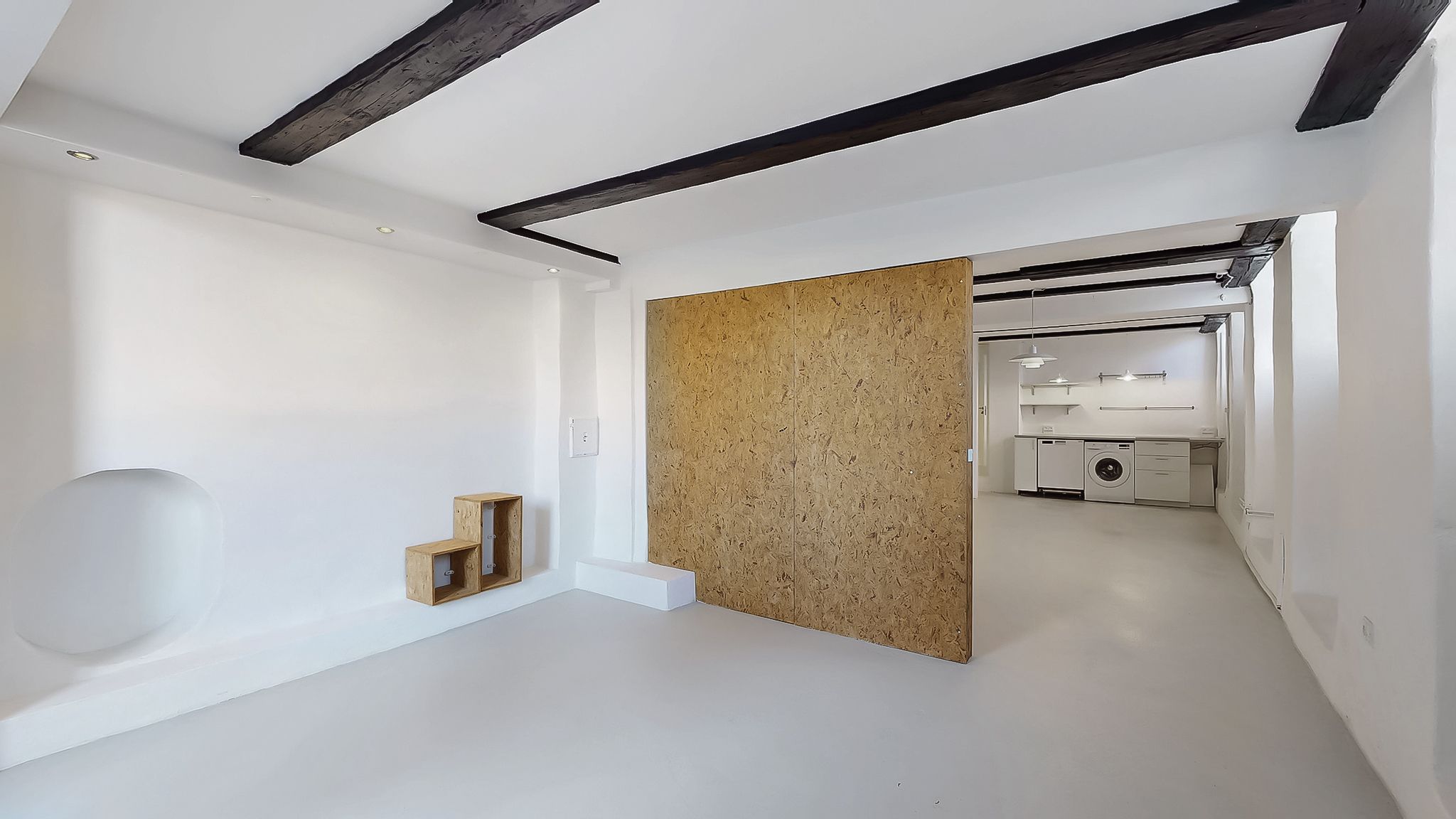 Minimalistisk stue med hvide vægge, lysegul gulv og lysekroner. Møbler og apparater er ikke synlige på billedet.